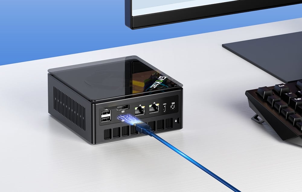 Cable connected to mini PC lying on white desk next to monitor and keyboard